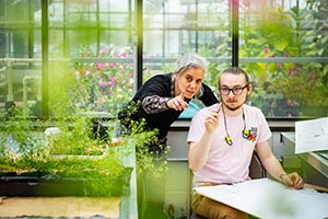 Professor talking with a student seated at a desk.
